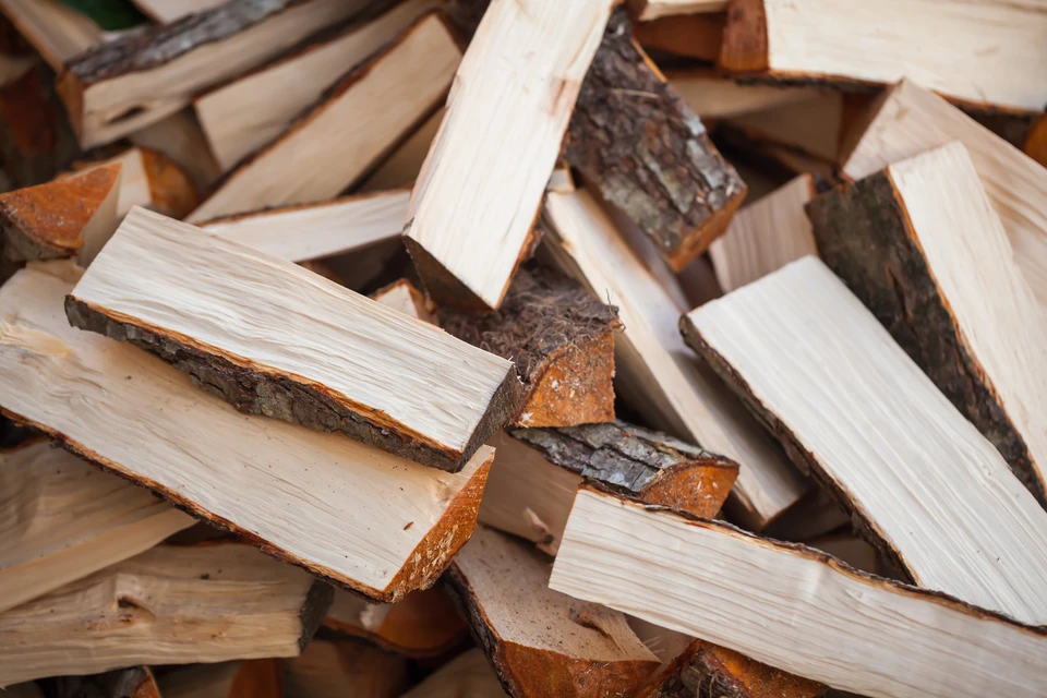 Tas de bûches de bois de chauffage fendues, empilées en désordre