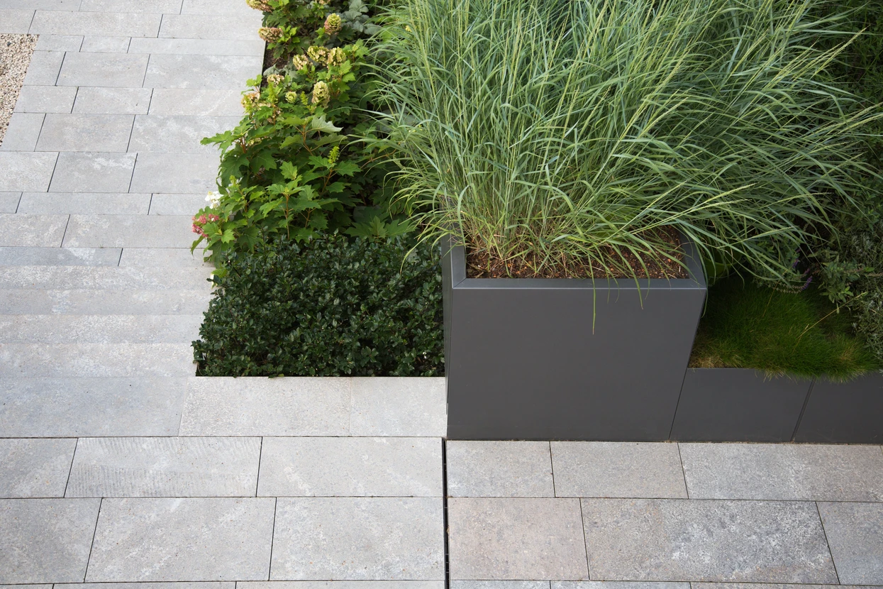 Conception de jardin et de terrasse avec un mélange moderne de matériaux de construction et de précieux objets de décoration de jardin et diverses plantes