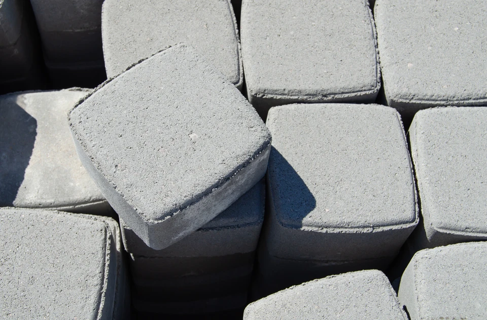 Chantier extérieur de pavage avec pavés autobloquants en béton gris empilés sur sol granulaire